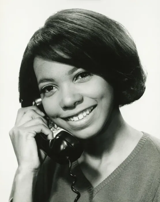 Framed Print : Young woman using phone in studio, smiling, (B&W), portrait Framed Print : Young woman using phone in studio, smiling, (B&W), portrait