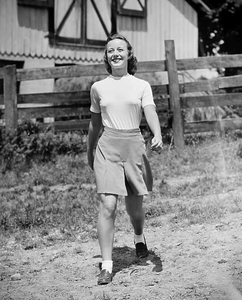 Young woman walking in front of cottage house (B&W)