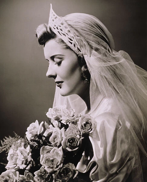 Young woman in wedding dress and bouquet in studio, (B&W), close-up