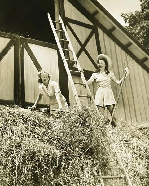Two young women pitching hay, (B&W)