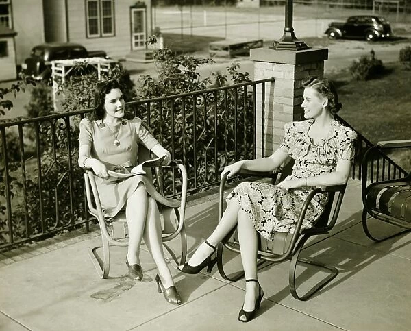 Two young women sitting on terrace, talking, (B&W)