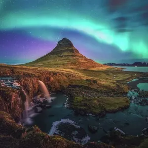 active aurora borealis storm display over iconic shape of mountain kirkjufell, Iceland