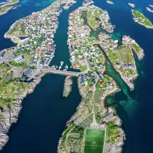 Aerial view, Henningsvaer with football stadium, rock islands in the sea off Bergen, Festvagtinden, Vestvagoey, Lofoten, Nordland, Norway Aerial view, Henningsvaer with football stadium, rock islands in the sea off Bergen, Festvagtinden, Vestvagoey, Lofoten, Nordland, Norway