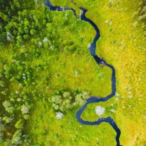 Aerial view of a small river flowing through marshland in Finland