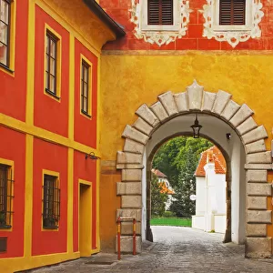 Arch And Cobblestone With An Orange And Yellow Building In Old Town