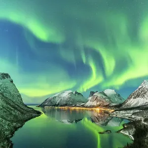The aurora borealis lights up in the sky and is reflected in the fjord. Northern Norway, Europe The aurora borealis lights up in the sky and is reflected in the fjord. Northern Norway, Europe