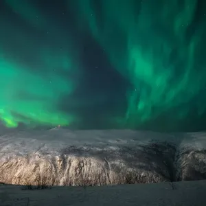 Aurora Borealis on a starry night behind a mountain, Tromso, Norway