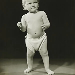 Baby (12-15 months) in diaper standing in studio, (B&W)