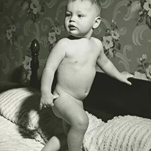 Baby (12-15 months) standing on bed, (B&W)