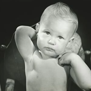 Baby boy (6-12 months) sitting in high chair, (B&W), portrait