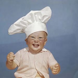 Baby boy wearing chefs hat, smiling, portrait