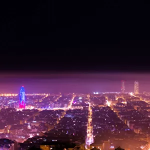 Barcelona cityscape with Sagrada Familia and Agbar tower illuminated at night between spring fog
