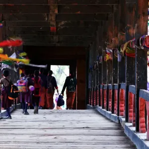 Bhutan, Paro, Paro Dzong, people crossing covered bridge, rear view Bhutan, Paro, Paro Dzong, people crossing covered bridge, rear view