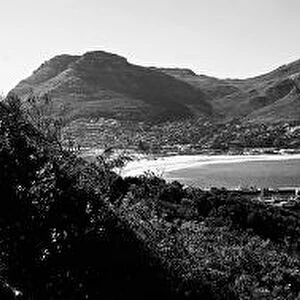A black and white panoramic picture of Hout Bay with Hout Bay Beach on the left and the marina and fishing harbour in the foreground. Chapmans Peak is in the background. Western Cape Province, South Africa