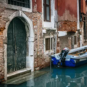 Boat moored by the townhouse door facing canal in Venice, Italy