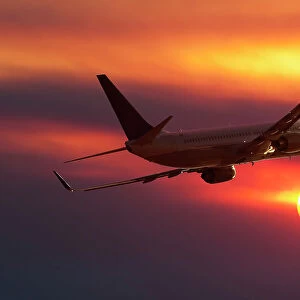 A Boeing 737 airliner flying into a sunset