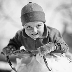 Boy (6-7) lying on sled in snow, (B&W), portrait