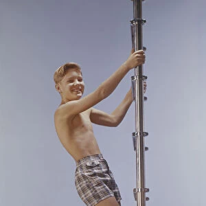 Boy climbing ladder, smiling, portrait