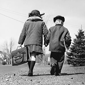 Boy and girl holding hands, walking to school