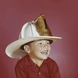 Boy wearing fireman hat, smiling, close-up