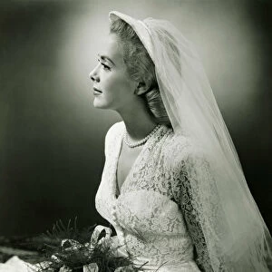 Bride with bouquet posing in studio, (B&W), portrait