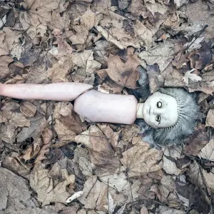 Broken doll lying in the front garden of an abandoned kindergarten, village in