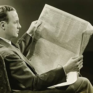 Businessman reading newspaper, (B&W)
