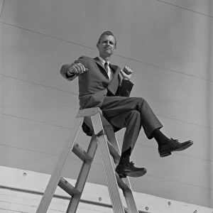 Businessman sitting on top of step ladder, portrait