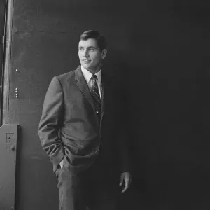 Businessman standing against black background, smiling