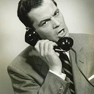 Businessman using phone in studio, (B&W), close-up