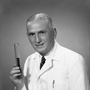 Chemist holding test tube in studio, (B&W), portrait