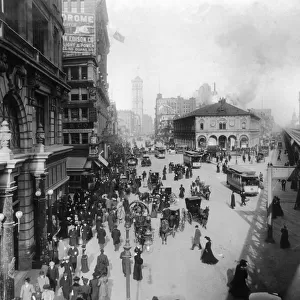 circa 1902: Crowds of people move through Herald Square on foot, in horse drawn carriages