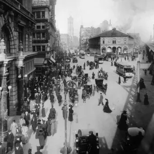circa 1902: Crowds of people move through Herald Square on foot, in horse drawn carriages