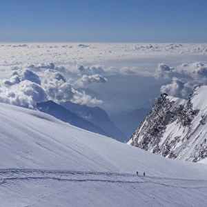 Two climbers above the clouds on Monte Rosa, Alps, Valle dAosta, Italy