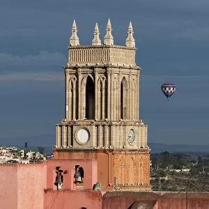 Clock tower and bells of the parish church with a hot air balloon flight in the distance