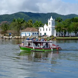 Colourful boat sailing with the pretty Brazilian town Paraty in the back ground Colourful boat sailing with the pretty Brazilian town Paraty in the back ground