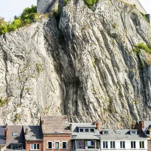 Colourful building fronts with steep cliff and medieval fortress on top