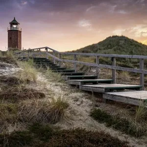 Colourful sunset behind the smallest lighthouse, the Quermarkenfeuer, on the North Frisian island of Sylt, Germany Colourful sunset behind the smallest lighthouse, the Quermarkenfeuer, on the North Frisian island of Sylt, Germany