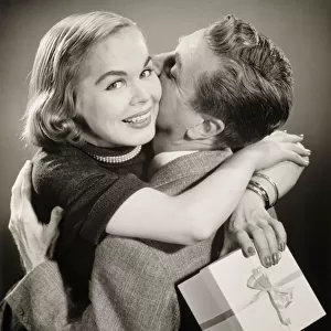 Couple hugging, woman holding gift, (B&W)