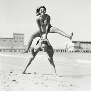 Couple playing leapfrog on beach, woman jumping over man