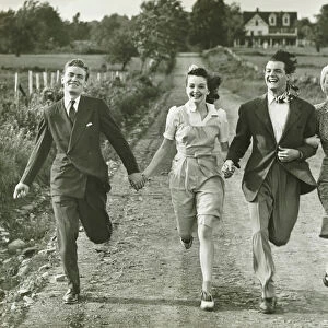 Two couples holding hands, running on footpath, (B&W)
