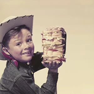 Cowboy holding sandwich, smiling, portrait