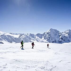 Cross-country skiers during the descent from Hintere Schoentaufspitze Mountain, overlooking Zufallspitze, Cevedale, Koenigsspitze and Zebru Mountains, Solda, Alto Adige, Italy, Europe