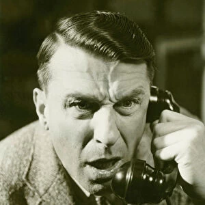 Distressed man on landline phone, (B&W), close-up