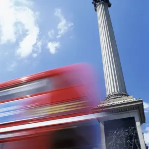 Double Decker Bus Driving past Nelsons Column on Trafalgar Square, Tourists Sitting on Steps, London, UK Double Decker Bus Driving past Nelsons Column on Trafalgar Square, Tourists Sitting on Steps, London, UK
