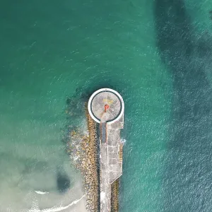 Drone shot above a small lighthouse on a pier, Looe, Cornwall, United Kingdom Drone shot above a small lighthouse on a pier, Looe, Cornwall, United Kingdom