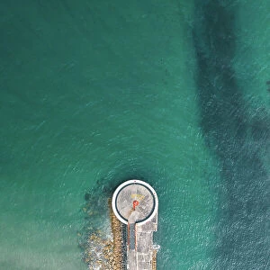 Drone shot above a small lighthouse on a pier, Looe, Cornwall, United Kingdom