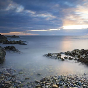 Early morning landscape of ocean over rocky shore with glowing sunrise - Findochty, Scotland