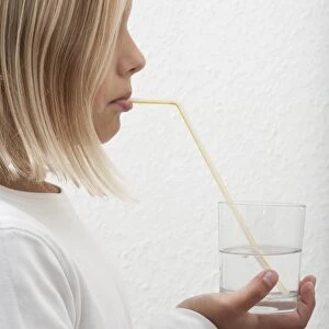 Eight-year-old girl drinking mineral water through a straw