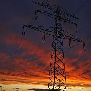 Electricity pylon against a red evening sky, Bavaria, Germany